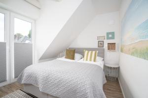 a white bedroom with a bed and a window at Kleines Glück in Scharbeutz