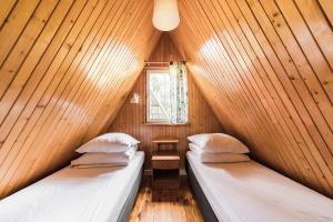 2 łóżka w drewnianym pokoju z oknem w obiekcie Ośrodek Wypoczynkowy Kalwa w Pasymiu