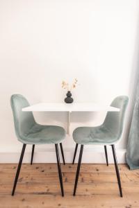 a white table and two green chairs in a room at Cosy Guestroom Bruges in Bruges