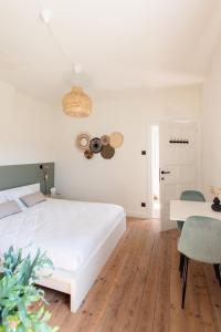 a white bedroom with a white bed and a table at Cosy Guestroom Bruges in Bruges