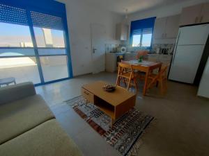 a living room with a couch and a table and a kitchen at Desert Path in Beʼer Ora