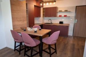 a kitchen with a wooden table and pink chairs at BG LUXIMMO APARTMENTS in Cluj-Napoca