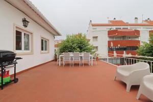a balcony with white chairs and tables on a building at Casa do Terraço in São Martinho do Porto