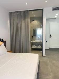 a bedroom with a large white bed and a bathroom at Vila D Boutique Hotel in Qeparo