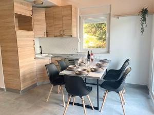 mesa de comedor con sillas negras y cocina en Apartment house GAIA, en Gajac