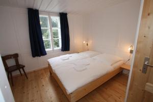 a bedroom with a bed with white sheets and a window at Chalet Hotel Krone in Göschenen