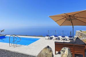 um pátio com um guarda-sol e cadeiras e uma piscina em Villa de la Luz em Tijarafe