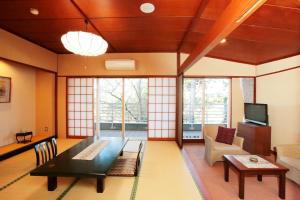 a living room with a table and a couch and a tv at Itsuura Kanko Hotel in Kitaibaraki