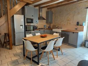 een keuken met een houten tafel en witte stoelen bij Troglo Bel Être in Langeais