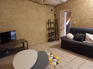 een woonkamer met een bank, een tafel en een tv bij Troglo Bel Être in Langeais
