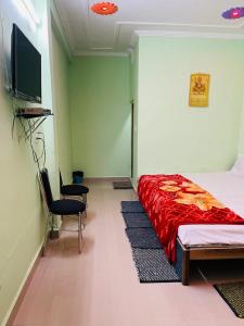 sypialnia z łóżkiem i 2 krzesłami oraz telewizorem z płaskim ekranem w obiekcie Anand Dham Guest House By WB Inn w mieście Sītāpur Mūāfi