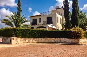 a large white house with trees and a brick driveway at Theos Club Villas in Polis Chrysochous