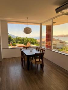 a dining room with a table and chairs and a large window at Apartments Angela in Cesarica