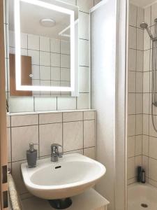 La salle de bains est pourvue d'un lavabo blanc et d'un miroir. dans l'établissement Helles und ruhiges Apartment direkt am Flughafen Leipzig Halle, à Schkeuditz