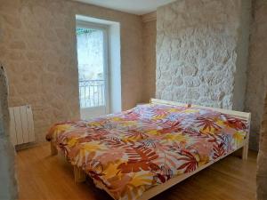 a bed with a colorful comforter in a bedroom at Troglo Bel Être in Langeais