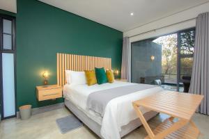 a bedroom with a large bed and a green wall at Kruger's Keep - Luxury Couples Haven in Marloth Park