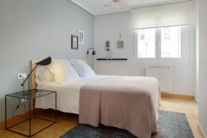 a white bedroom with a white bed and a window at Mundaiz by FeelFree Rentals in San Sebastián