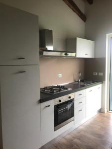 uma cozinha com armários brancos e um forno com placa de fogão em THE RANCH Apartment 4 Capalbio em Pescia Romana