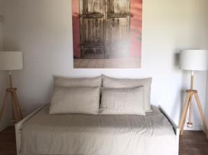 a bed in a room with two lamps and a painting on the wall at THE RANCH Apartment 4 Capalbio in Pescia Romana +20 photos