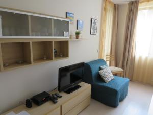 een woonkamer met een blauwe stoel en een flatscreen-tv bij Rivendell Apartments Borovets Gardens complex in Borovets