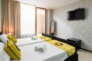 Habitación de hotel con 2 camas con sábanas amarillas en Aura Plaza Hotel en Tiflis