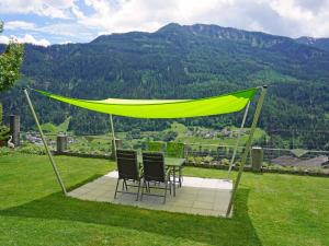 a table and chairs under a yellow canopy on a lawn at Apartment Muehlbach by Interhome in Fliess