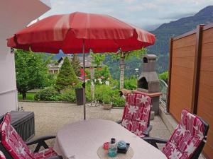 uma mesa e cadeiras com um guarda-sol vermelho na varanda em Apartment Evi by Interhome em Fliess