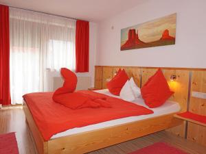 Schlafzimmer mit einem Bett mit roter Bettwäsche und roten Kissen in der Unterkunft Apartment Evi by Interhome in Fliess