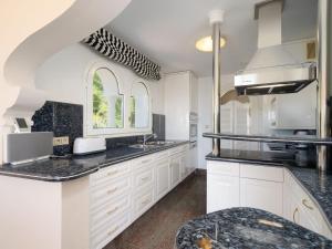 a kitchen with white cabinets and black counter tops at Villa Luxemburg by Interhome in Fanadix