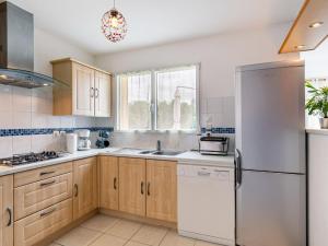 Una cocina con gabinetes de madera y un refrigerador blanco. en Holiday Home Ty Fañch by Interhome, en Kerlouan