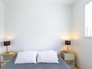 ein Schlafzimmer mit weißen Wänden und ein Bett mit zwei Nachttischen in der Unterkunft Holiday Home Ty Fañch - KER227 by Interhome in Kerlouan