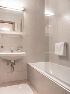 W łazience znajduje się umywalka, wanna i lustro. w obiekcie La Tombola Appartements w mieście Gerlos