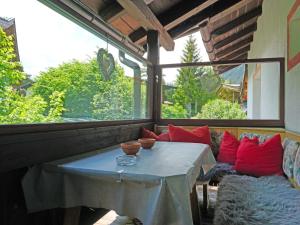 um alpendre com uma mesa e um sofá com almofadas vermelhas em Apartment Föhrenheim - SFE202 by Interhome em Leutasch