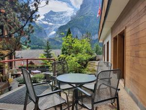 een tafel en stoelen op een balkon met uitzicht op de bergen bij Apartment Chalet Abendrot-20 by Interhome in Grindelwald