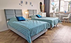 two beds with blue pillows in a bedroom at Kapitan Marina Gdynia Rental Apt in Gdynia