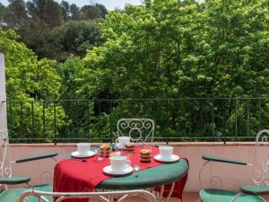 a table with a red table cloth and chairs on a balcony at Apartment S'Esquirols III by Interhome in Begur