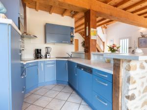 Una cocina con gabinetes azules y techo de madera. en Holiday Home Les Mouettes by Interhome, en Hauteville-sur-Mer