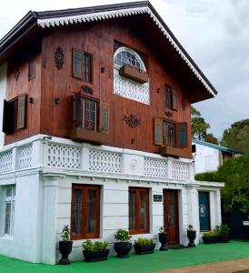 a wooden house with windows and potted plants in front of it at The Golf Green City Bungalow in Nuwara Eliya