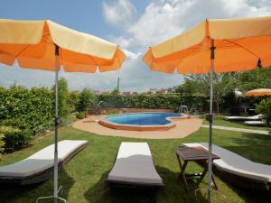 a pool with two umbrellas and two lounges and two chairs at Apartment Zwei Rosen - PUL553 by Interhome in Fondole
