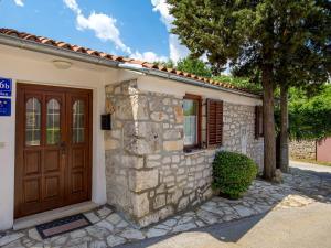 a stone house with a wooden door and a tree at Holiday Home Rotonda - LBN304 by Interhome in Kršan