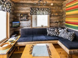 uma sala de estar com um sofá azul e paredes de madeira em Holiday Home Lomaylläs maja-keloluppo by Interhome em Ylläsjärvi