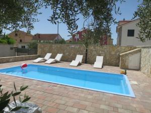a swimming pool in a backyard with chairs and a fence at Holiday Home Tina - BIG120 by Interhome in Biograd na Moru