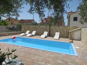 a swimming pool in a backyard with chairs and a fence at Holiday Home Tina by Interhome in Biograd na Moru