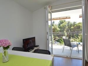 ein Wohnzimmer mit einem Tisch, einem TV und einem Balkon in der Unterkunft Apartment Ivka-3 by Interhome in Tribunj