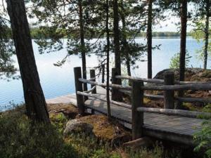 un banc en bois assis sur le côté d'un lac dans l'établissement Holiday Home Koivukallio by Interhome, à Mataramäki