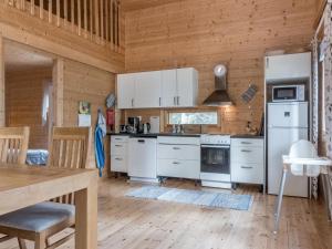 a kitchen with white appliances and a wooden wall at Holiday Home Pursiranta by Interhome in Keränen