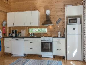 a kitchen with white appliances and a wooden wall at Holiday Home Pursiranta by Interhome in Keränen