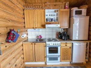 La cuisine est équipée d'armoires en bois, d'une cuisinière et d'un réfrigérateur. dans l'établissement Holiday Home Jänkäluppo i by Interhome, à Äkäslompolo