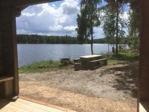 a picnic table and a bench next to a lake at Holiday Home Koivuranta by Interhome in Petäjävesi