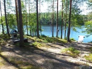 a picnic table in the woods next to a lake at Holiday Home Aili by Interhome in Arrakoski